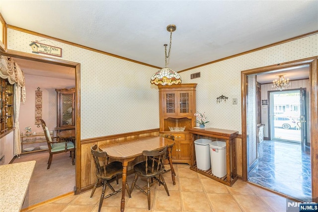dining area featuring visible vents, crown molding, wainscoting, a chandelier, and wallpapered walls