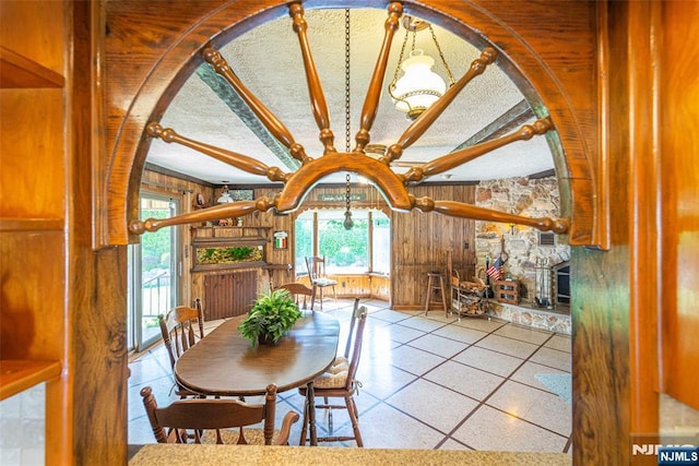 dining area with arched walkways, wood walls, a chandelier, and beam ceiling