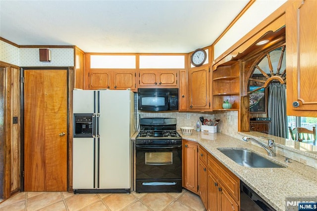 kitchen featuring brown cabinetry, open shelves, light stone counters, a sink, and black appliances