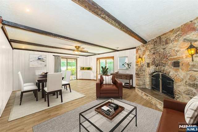 living area with a textured ceiling, visible vents, a fireplace, beam ceiling, and wood finished floors