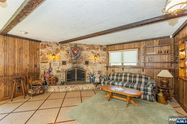 living room featuring beamed ceiling, wood walls, and a textured ceiling