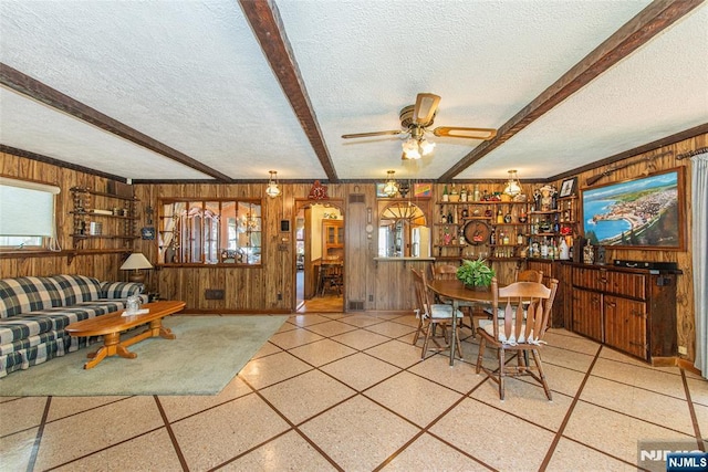 dining area with beam ceiling, arched walkways, a textured ceiling, wood walls, and a ceiling fan