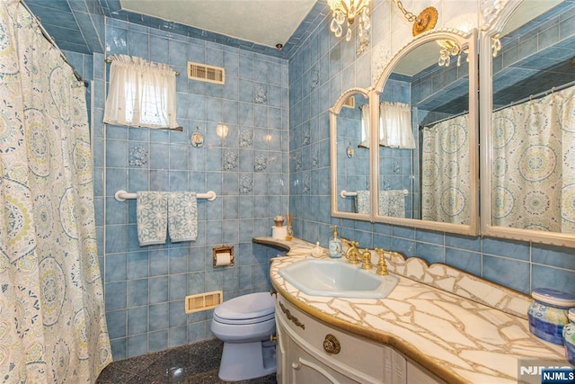 full bath featuring visible vents, vanity, toilet, and tile walls