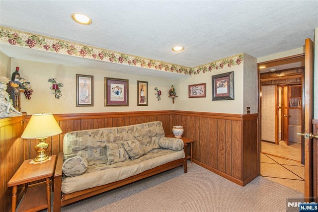 carpeted living room featuring recessed lighting, wainscoting, wood walls, and a textured ceiling
