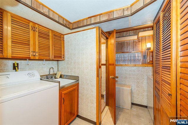 laundry room featuring washer / clothes dryer, tile walls, a sink, and cabinet space