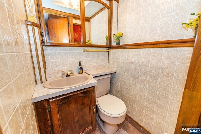 half bath featuring tile walls, vanity, and toilet