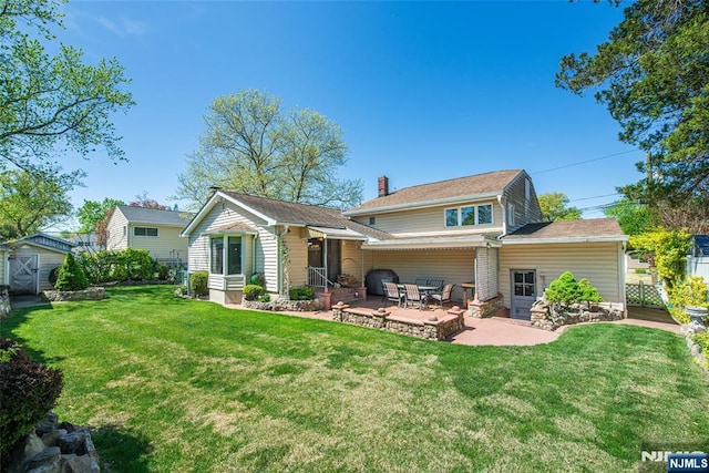 back of property with a chimney, a lawn, an outbuilding, a storage unit, and a patio