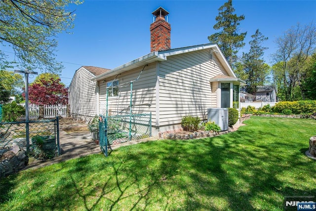 exterior space with a lawn, fence, a chimney, and cooling unit