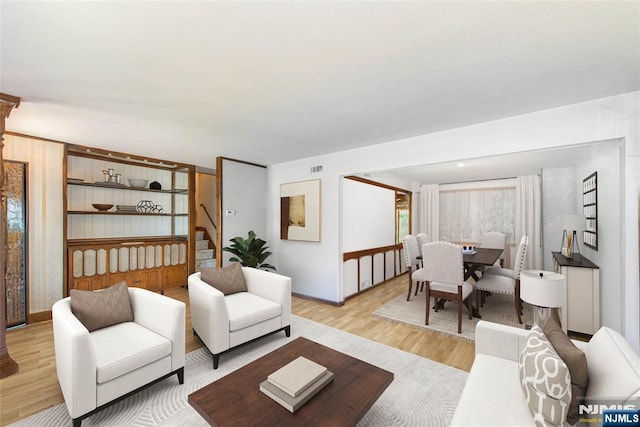 living room with light wood-style floors, stairs, and baseboards