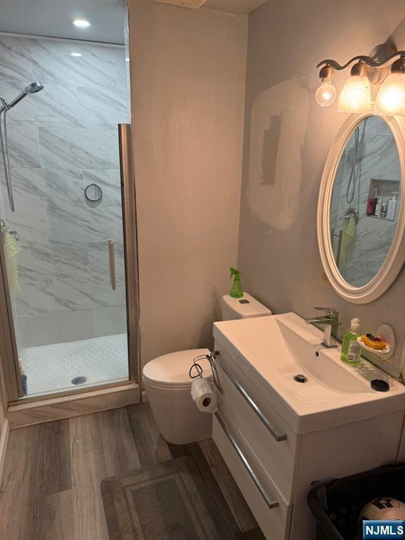 full bathroom with toilet, a shower stall, wood finished floors, and vanity