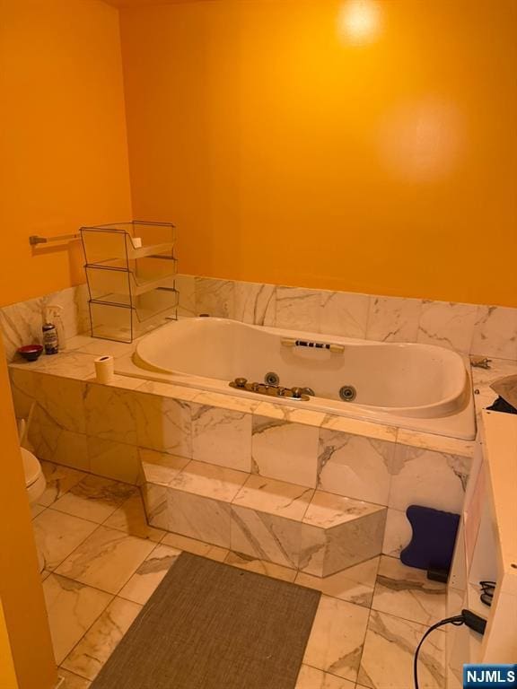 full bathroom with a garden tub and marble finish floor