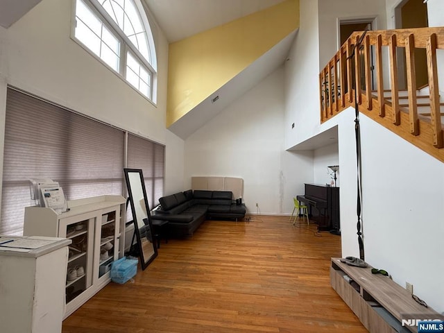 living room featuring light wood-style flooring and a towering ceiling