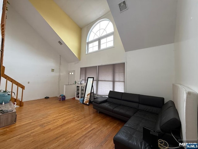 living room featuring high vaulted ceiling, baseboards, wood finished floors, and visible vents