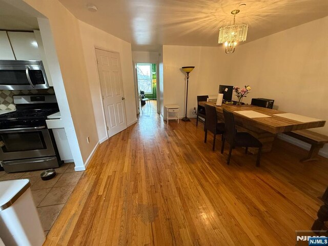 dining space with an inviting chandelier, baseboards, and light wood-type flooring