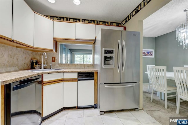 kitchen featuring light countertops, white cabinets, a chandelier, a sink, and stainless steel appliances