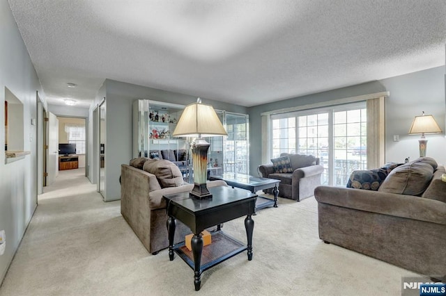 living room featuring light carpet, a textured ceiling, and a wealth of natural light