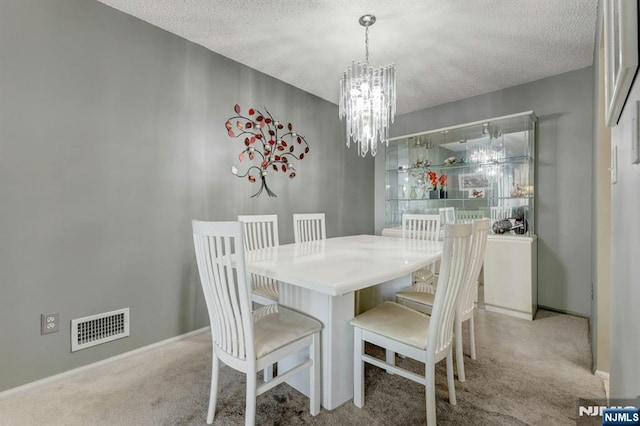 dining room with an inviting chandelier, carpet flooring, a textured ceiling, and visible vents