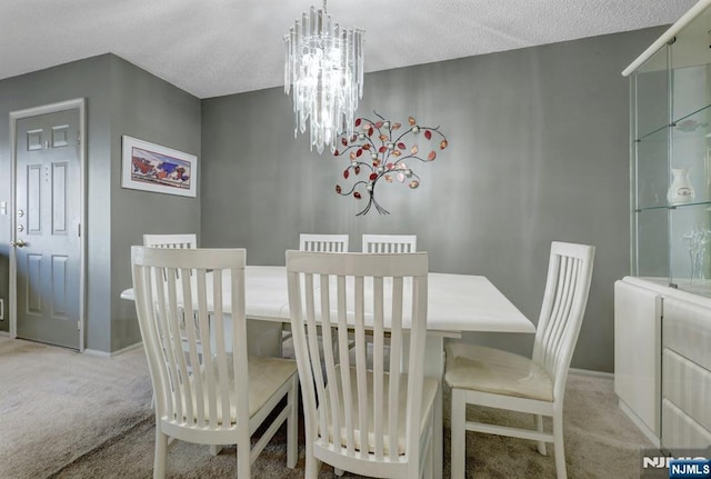 dining space with a textured ceiling, baseboards, a notable chandelier, and light carpet