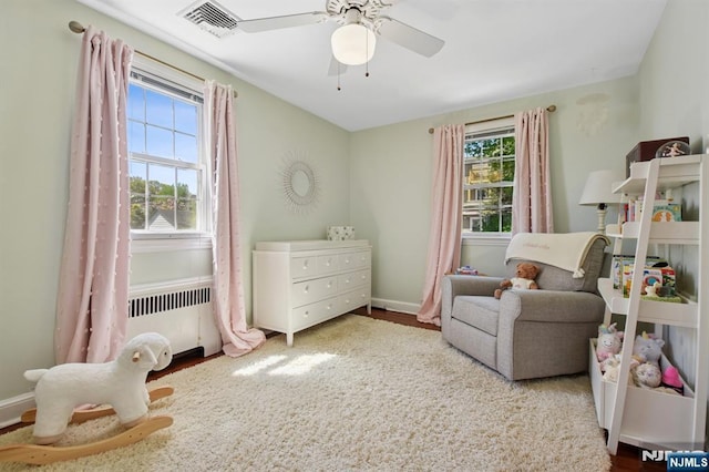 bedroom featuring visible vents, a ceiling fan, wood finished floors, and multiple windows