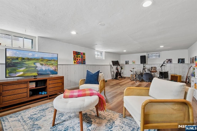 living room with a textured ceiling, wainscoting, wood finished floors, wooden walls, and recessed lighting