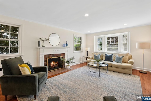 living room featuring crown molding, baseboards, a brick fireplace, and wood finished floors
