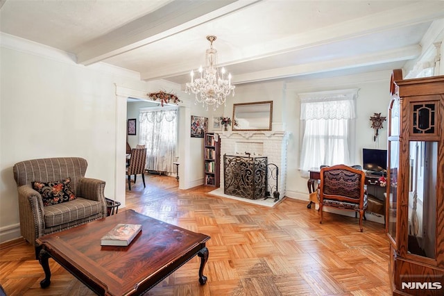 living area with baseboards, beamed ceiling, a brick fireplace, and a notable chandelier