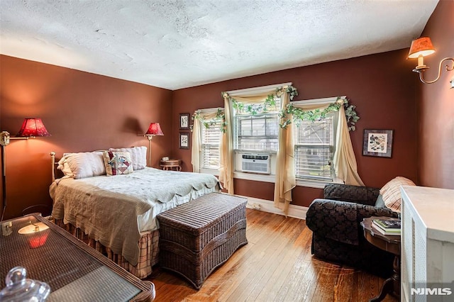bedroom featuring wood-type flooring, a textured ceiling, baseboards, and multiple windows