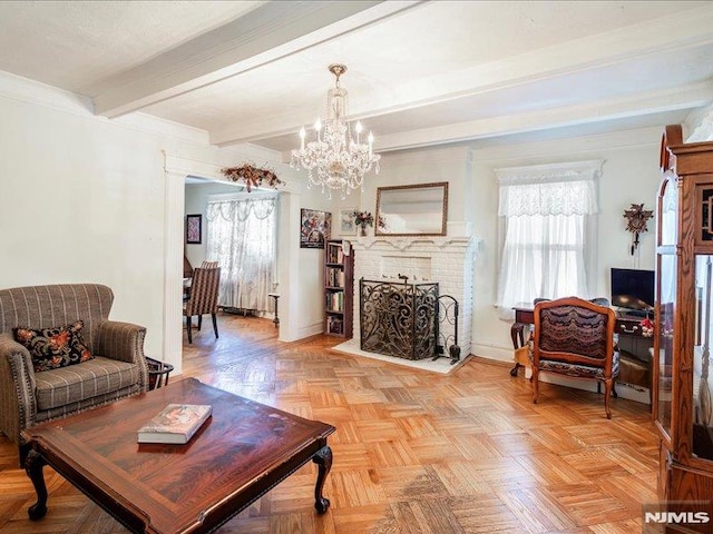 living area with baseboards, a brick fireplace, beam ceiling, and a chandelier