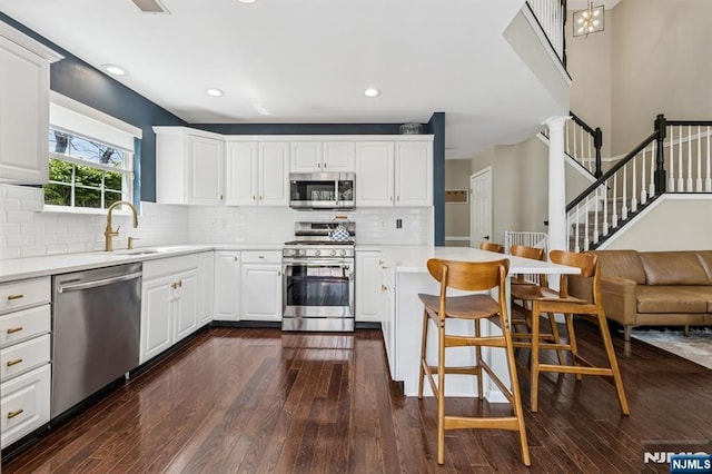 kitchen featuring stainless steel appliances, dark wood-style floors, a sink, and a peninsula