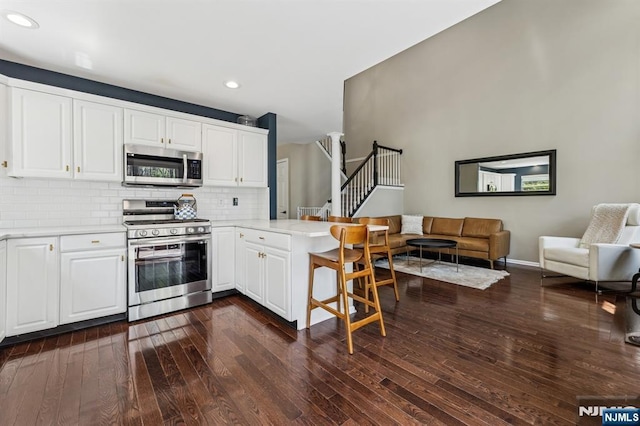 kitchen with recessed lighting, dark wood-style flooring, stainless steel appliances, and a peninsula