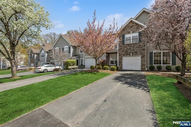 view of front of house with a garage, driveway, brick siding, and a front yard