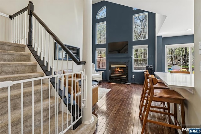 foyer with a glass covered fireplace, a high ceiling, dark wood-style floors, and stairway