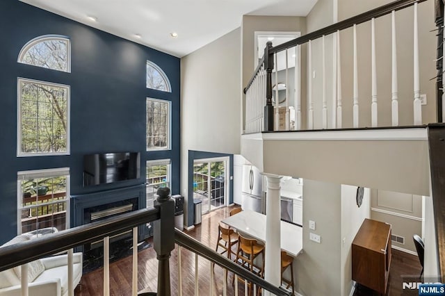 interior space with plenty of natural light, a fireplace, wood finished floors, and a towering ceiling