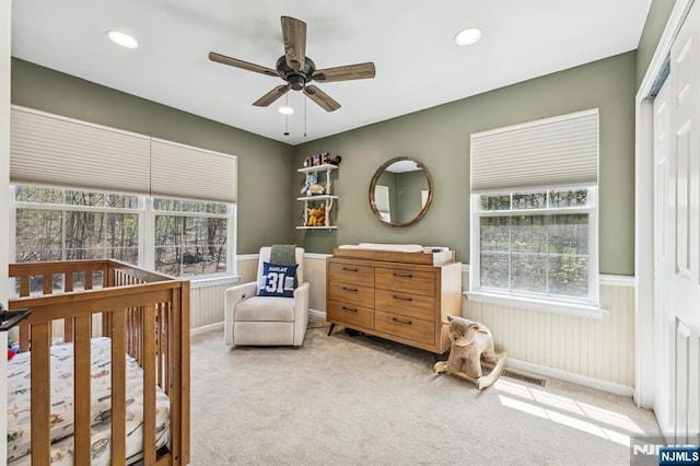 bedroom with a wainscoted wall, multiple windows, carpet flooring, and visible vents