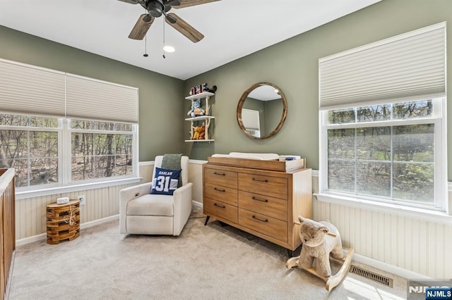 living area featuring visible vents, a ceiling fan, baseboards, and light carpet