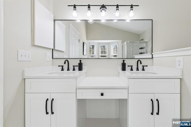 bathroom with double vanity, a shower stall, and a sink