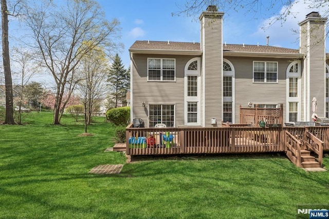 back of property with a lawn, a deck, and a chimney