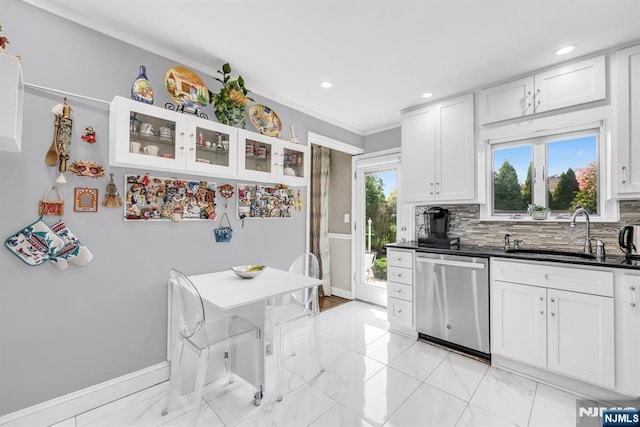 kitchen featuring stainless steel dishwasher, crown molding, baseboards, white cabinets, and a sink