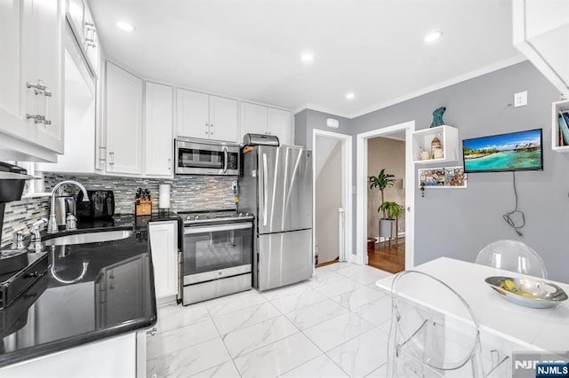 kitchen featuring dark countertops, tasteful backsplash, a sink, white cabinets, and stainless steel appliances