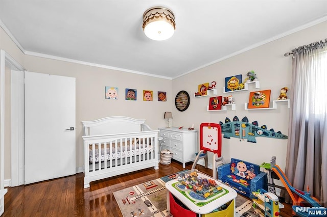 bedroom featuring crown molding, a crib, and wood finished floors