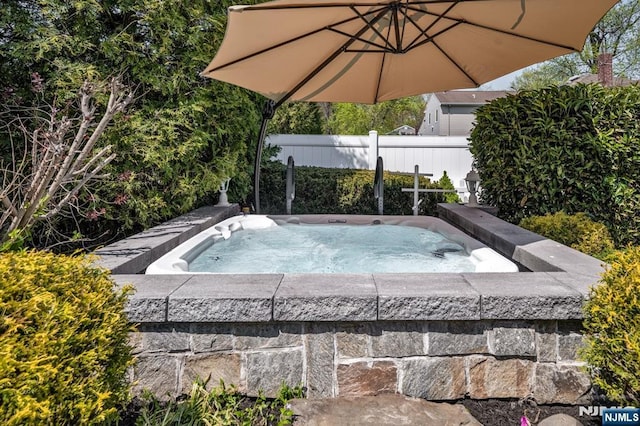 view of pool with fence and a hot tub