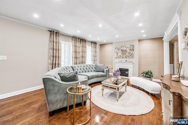 living room featuring crown molding, recessed lighting, baseboards, and a glass covered fireplace