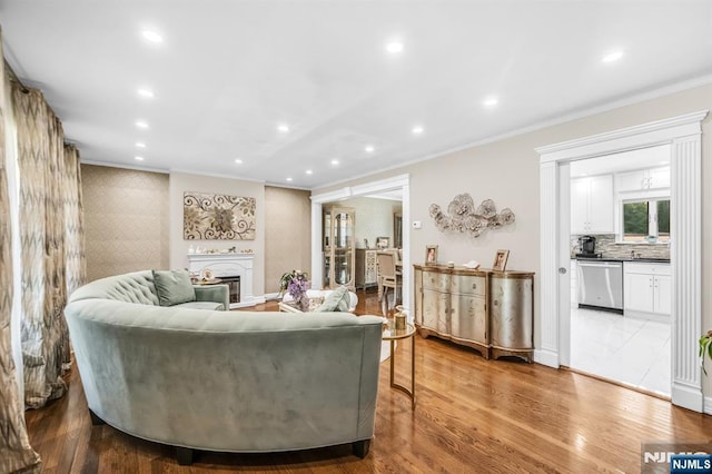 living room featuring crown molding, recessed lighting, wood finished floors, and a fireplace