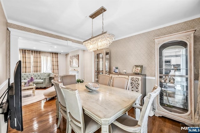 dining area with wood-type flooring, crown molding, and wallpapered walls
