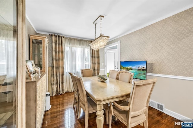 dining room with wallpapered walls, baseboards, dark wood-type flooring, visible vents, and ornamental molding