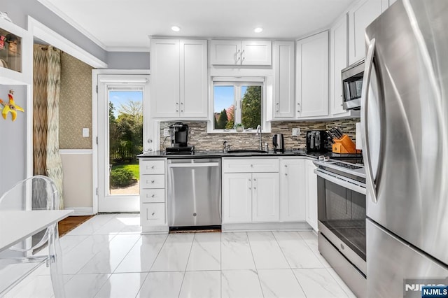 kitchen featuring white cabinetry, dark countertops, appliances with stainless steel finishes, and a sink