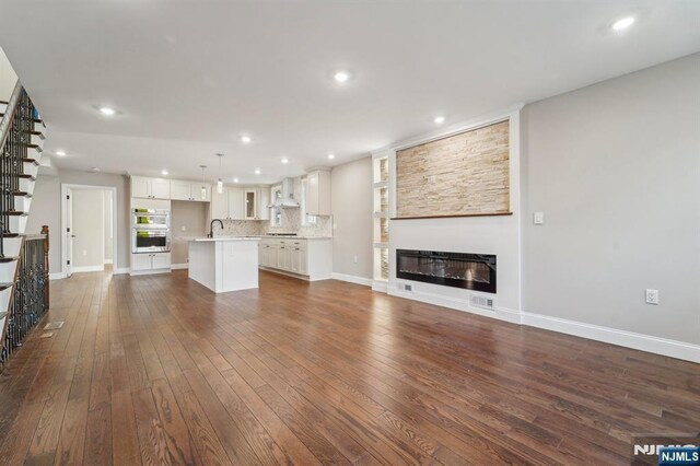 119 Lenox Ave, New Milford, NJ 07646 - unfurnished living room featuring a glass covered fireplace, dark wood-style flooring, recessed lighting, and a sink