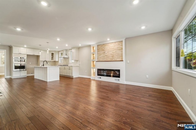 119 Lenox Ave, New Milford, NJ 07646 - unfurnished living room featuring dark wood-style flooring, recessed lighting, and a sink