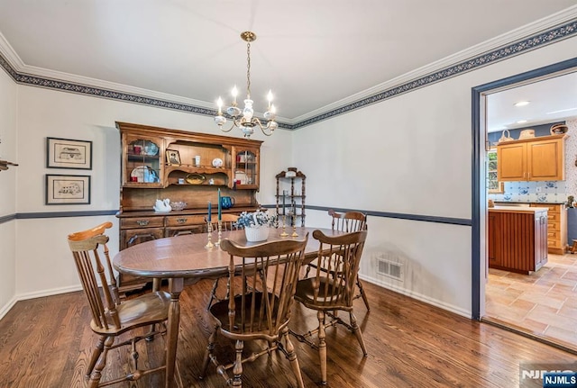 dining area with an inviting chandelier, crown molding, visible vents, wood finished floors, and baseboards