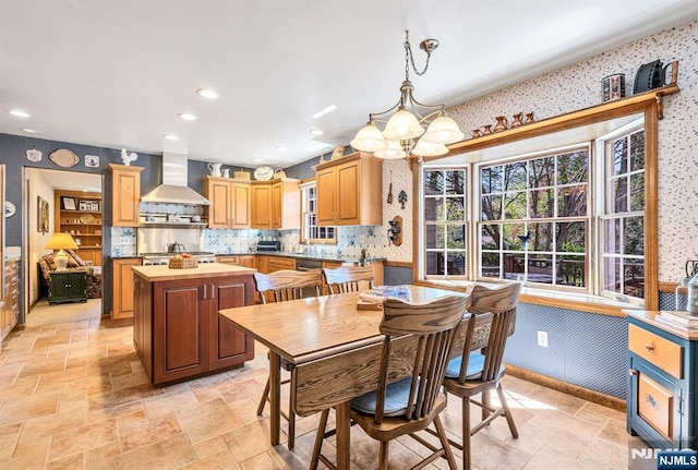 dining space featuring recessed lighting, wallpapered walls, an inviting chandelier, and stone tile flooring